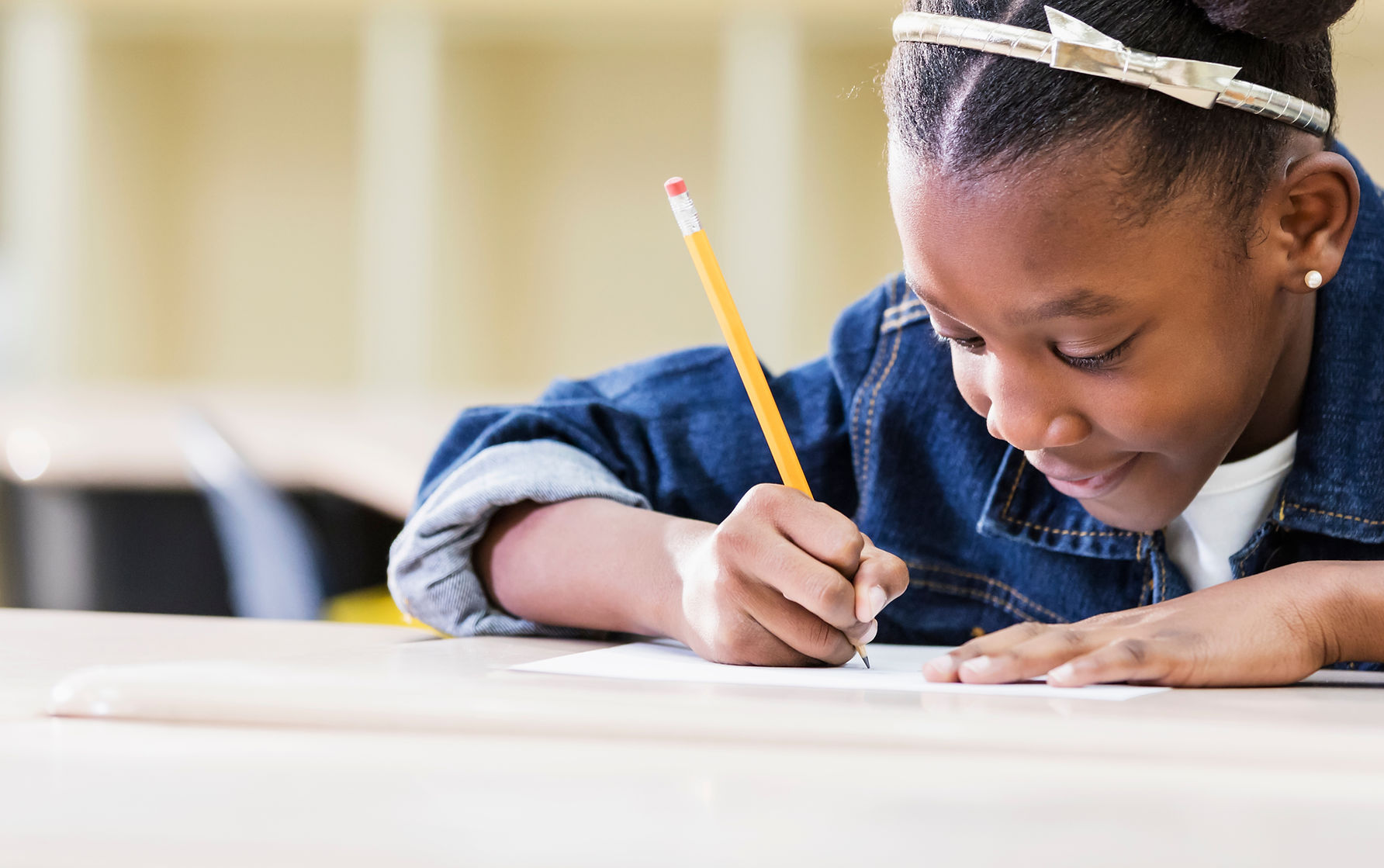 Student writing with a pencil at her desk